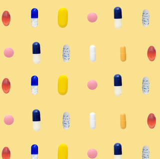 a bunch of different coloredshaped pills in rows on yellow background a bunch of different coloredshaped pills in rows on yellow background